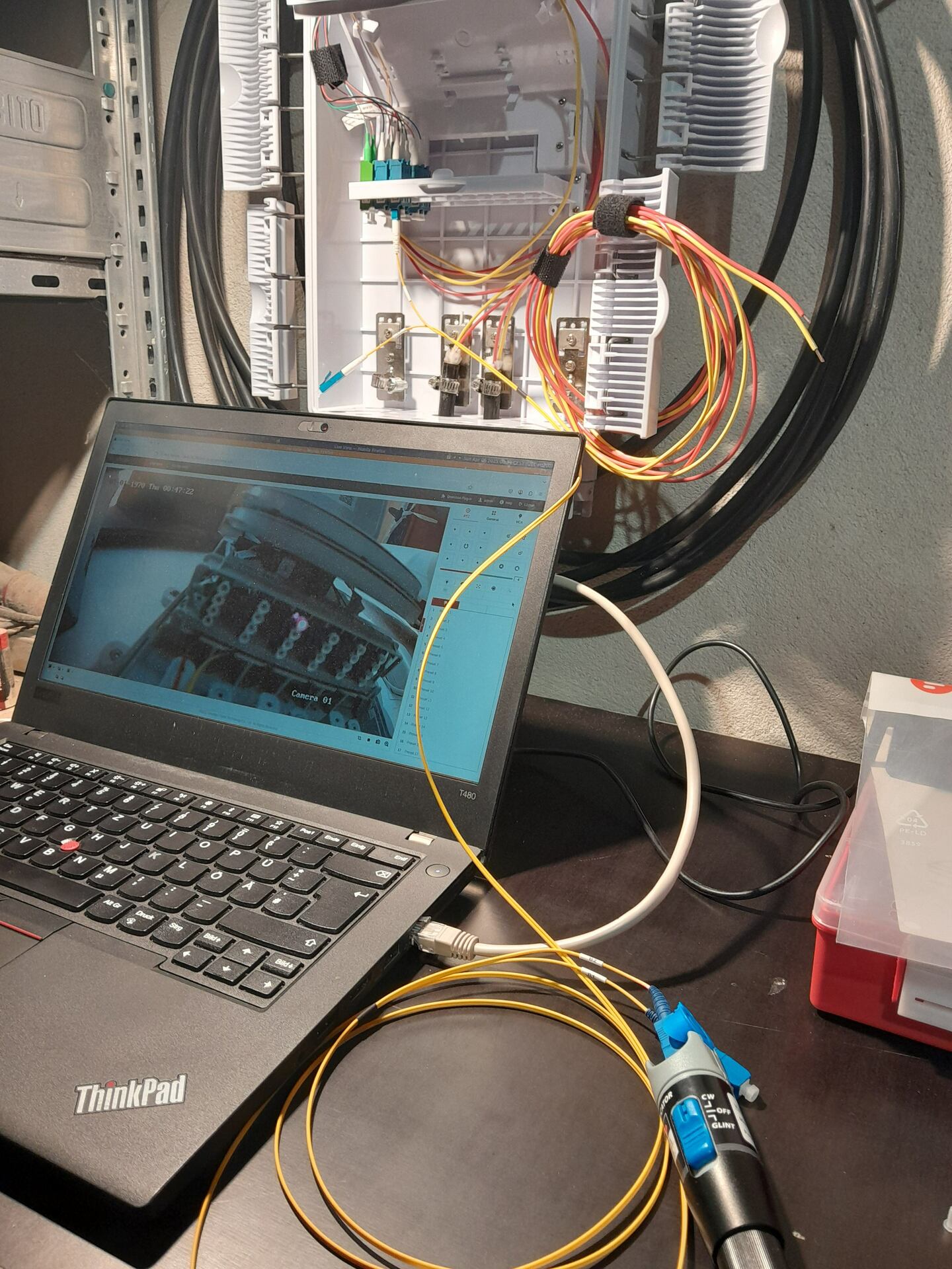 Laptop screen showing the feed from a camera looking at an fiber optic coupler illuminated in red